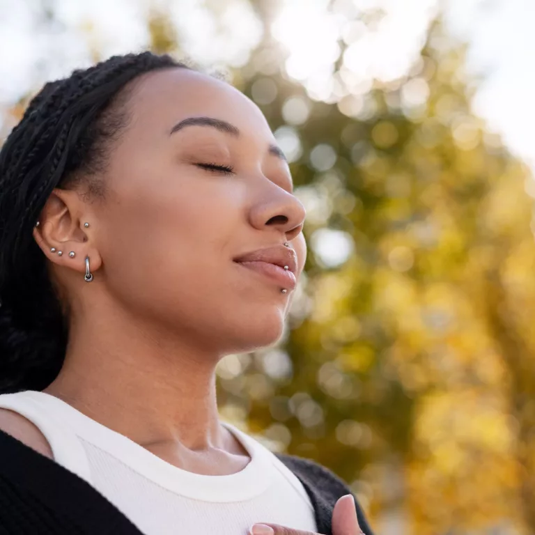 Cheerful African American woman meditating outdoors feeling tranquil breath, copy space. Beautiful female with closed eyes relaxing. Advertisement concept